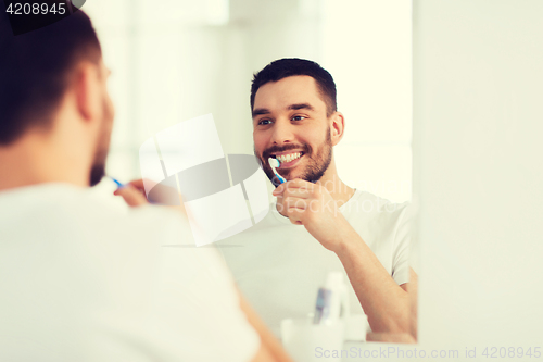 Image of man with toothbrush cleaning teeth at bathroom