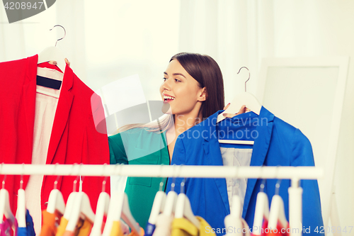 Image of happy woman choosing clothes at home wardrobe