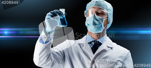 Image of scientist in mask holding flask with chemical