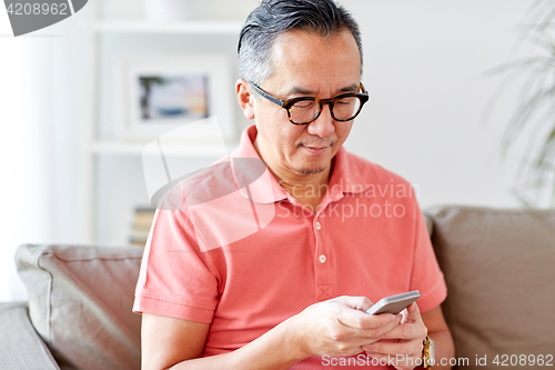 Image of man with smartphone sitting on sofa at home