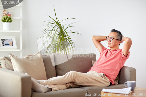 Image of man in glasses relaxing on sofa at home