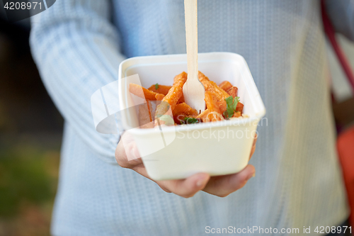 Image of close up of hand holding plate with sweet potato