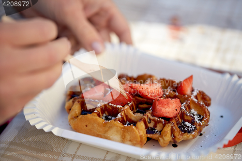 Image of close up of woman eating waffle with strawberry