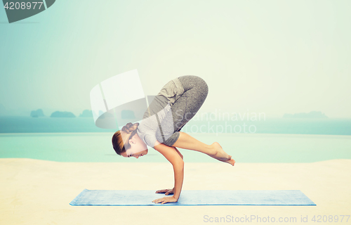 Image of woman making yoga in crane pose on mat