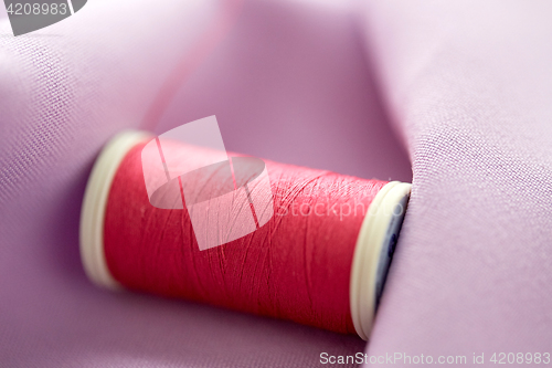 Image of red thread spool on cloth