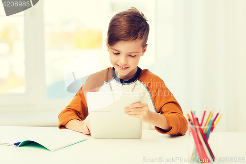 Image of smiling boy with tablet pc and notebook at home