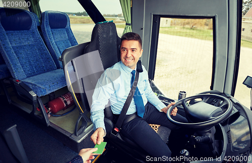 Image of bus driver taking ticket or card from passenger