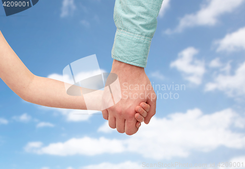 Image of father and child holding hands over blue sky