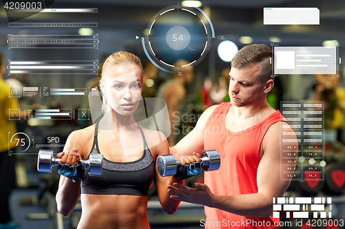 Image of young couple with dumbbells flexing muscles in gym