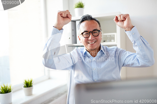 Image of happy businessman with laptop at office