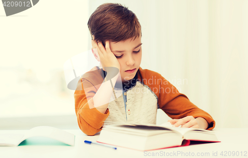 Image of student boy reading book or textbook at home