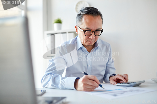 Image of businessman with calculator and papers at office