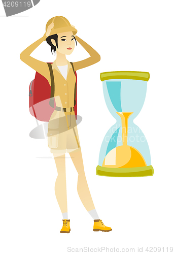 Image of Worried asian traveler woman looking at hourglass.