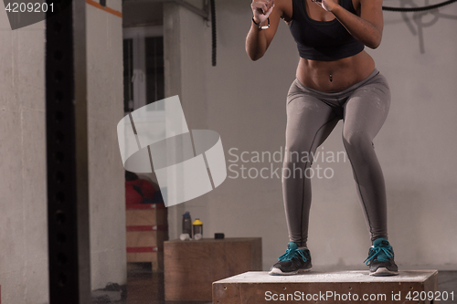 Image of black woman is performing box jumps at gym