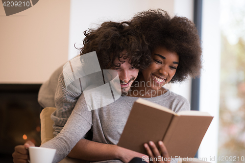 Image of multiethnic couple hugging in front of fireplace