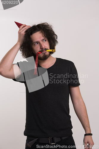 Image of Portrait of a man in party hat blowing in whistle