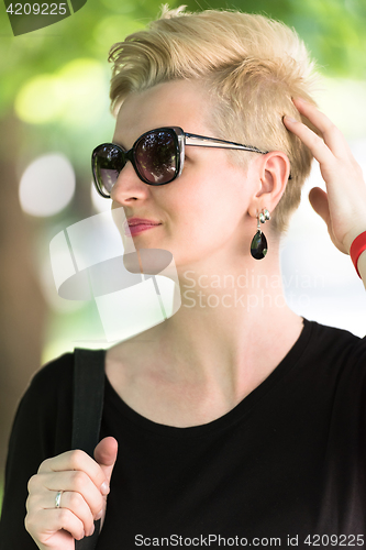 Image of young woman with short blond hair and sunglasses