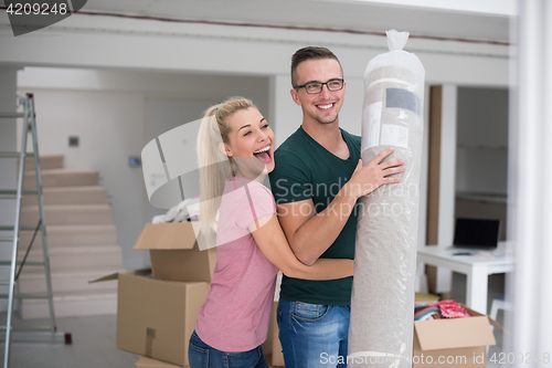 Image of couple carrying a carpet moving in to new home