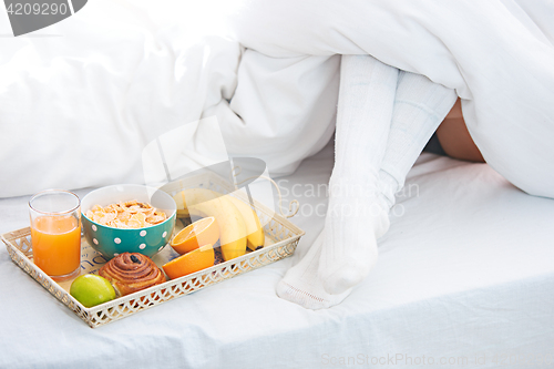 Image of Partial view of female legs and breakfast on bed