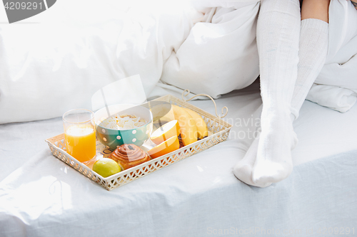 Image of Partial view of female legs and breakfast on bed