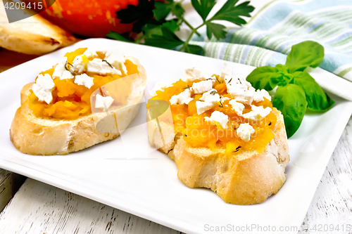 Image of Bruschetta with pumpkin and feta in white plate on board