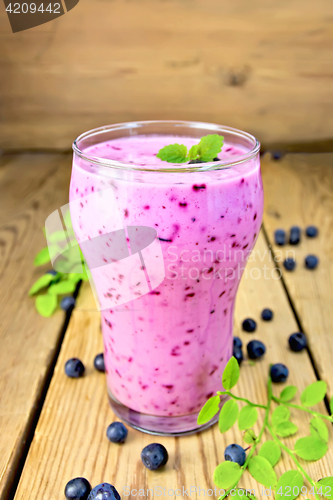 Image of Milkshake with blueberries in glass on wooden table