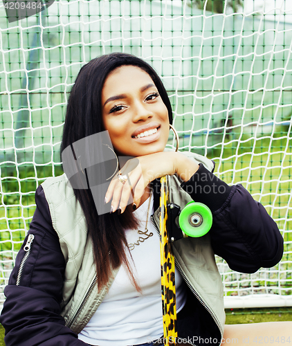 Image of cool pretty smiling afro-american happy young woman with skate b