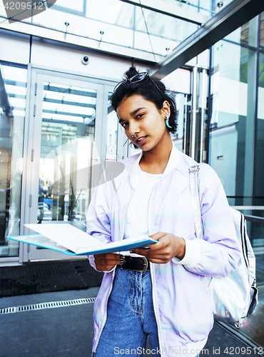 Image of young cute indian girl at university building sitting on stairs 