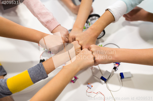 Image of happy children making fist bump at robotics school