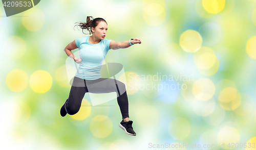 Image of happy sporty young woman jumping in fighting pose