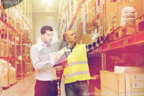 Image of worker and businessmen with clipboard at warehouse