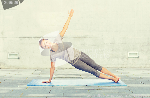 Image of woman making yoga in side plank pose on mat