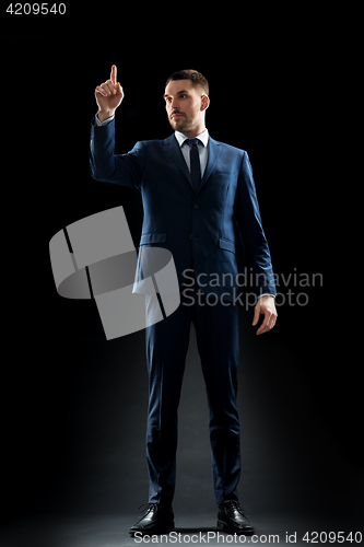 Image of businessman in suit touching something invisible