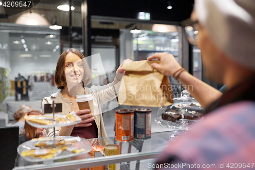 Image of woman taking paper bag from seller at cafe