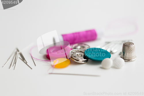 Image of sewing buttons, needles, pins and thread spool