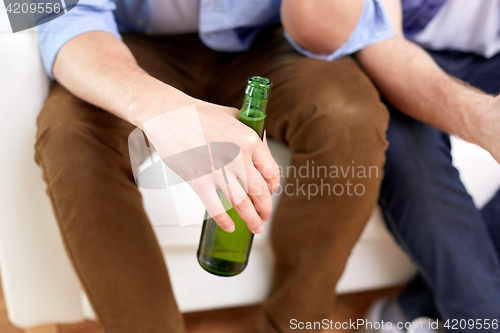 Image of men with beer bottles sitting on sofa at home