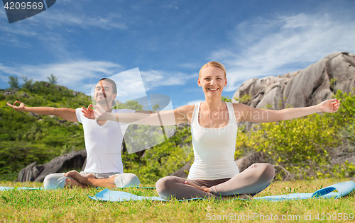 Image of happy couple making yoga exercises outdoors