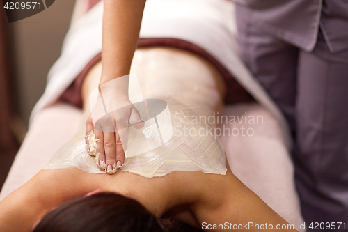 Image of woman having back massage with cream at spa