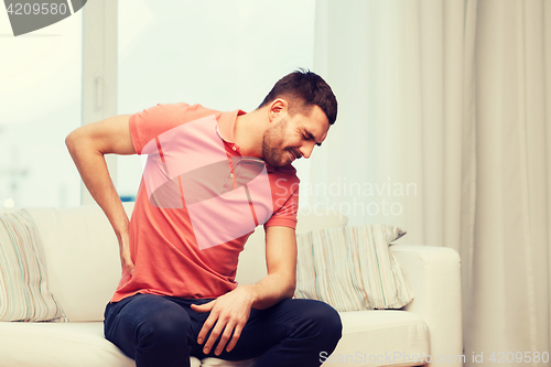 Image of unhappy man suffering from backache at home