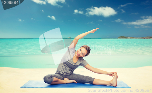 Image of happy woman making yoga and stretching on beach 