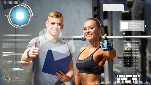 Image of smiling young woman with personal trainer in gym