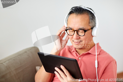 Image of man with tablet pc and headphones at home