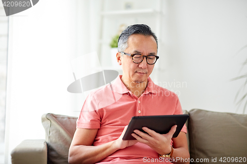 Image of man with tablet pc sitting on sofa at home