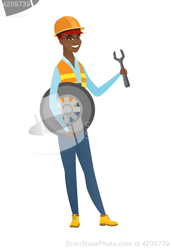 Image of Young mechanic with tyre and spanner.