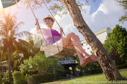 Image of Brunette at palm trees swinging