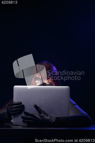 Image of Robber in mask holds laptop