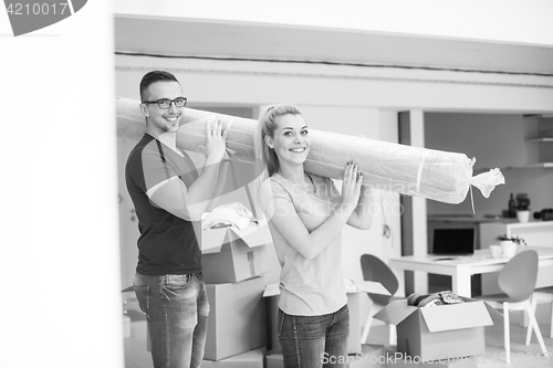 Image of couple carrying a carpet moving in to new home