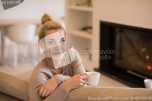 Image of woman with a mug near a fireplace