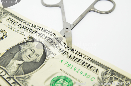 Image of Scissors cut through a dollar bill