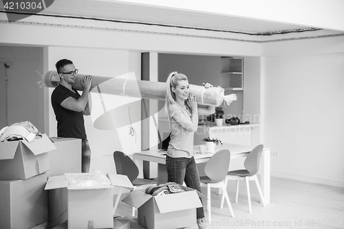 Image of couple carrying a carpet moving in to new home